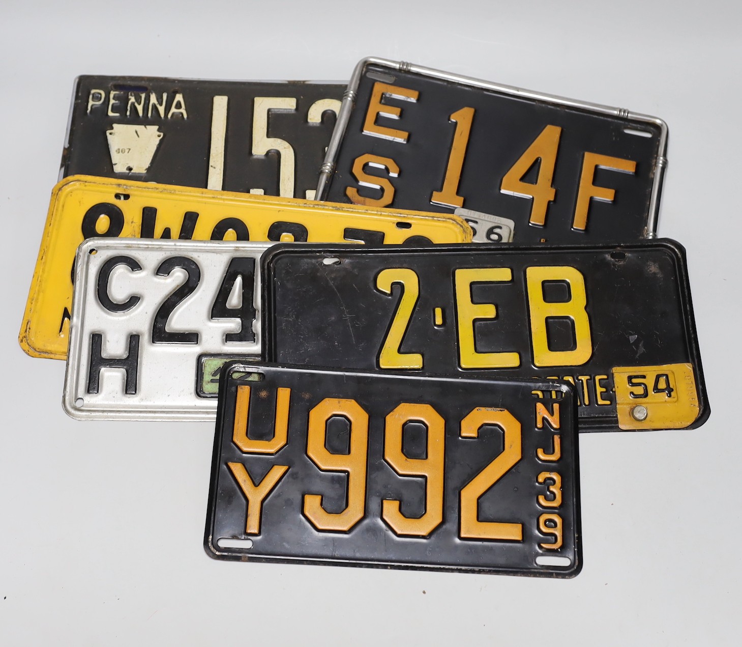 Eight New York and other car number plates, with badges attached